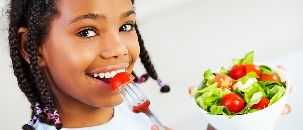 criança come frutas e legumes
