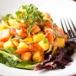 Salada de folhas com frutas tropicais e nozes caramelizadas